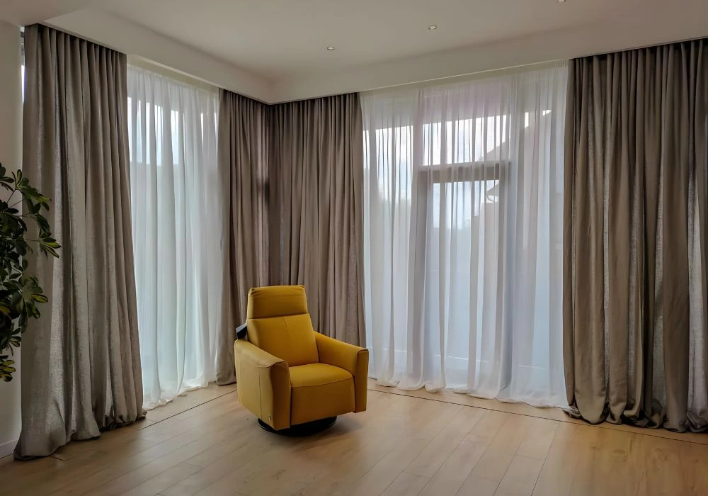 Beige wave fold curtains for luxury corner windows.