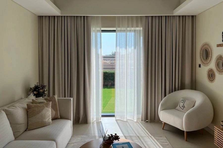 Beige blackout curtains with white sheer layers.