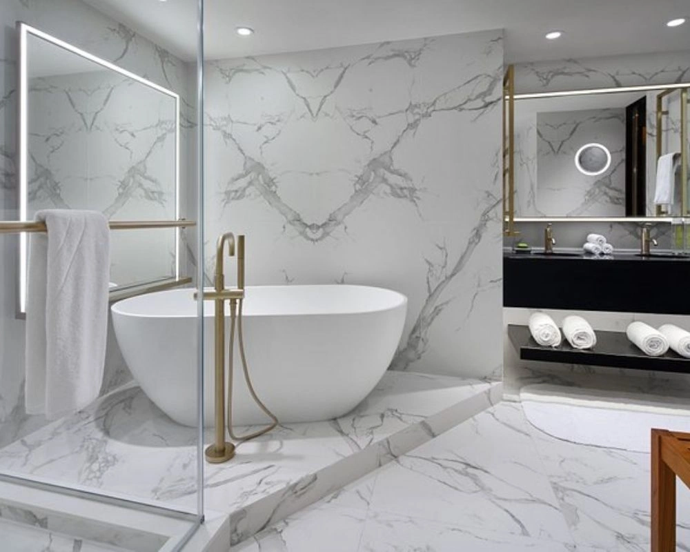 Modern white marble bathroom with gold standing faucet.