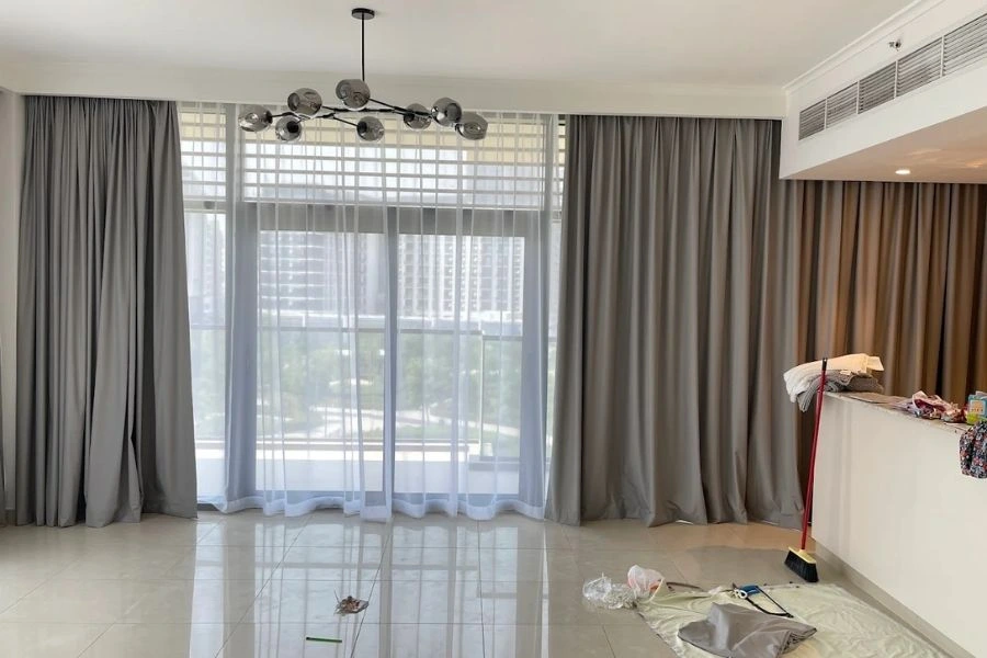 Grey apartment curtains with white sheer fabric layers.