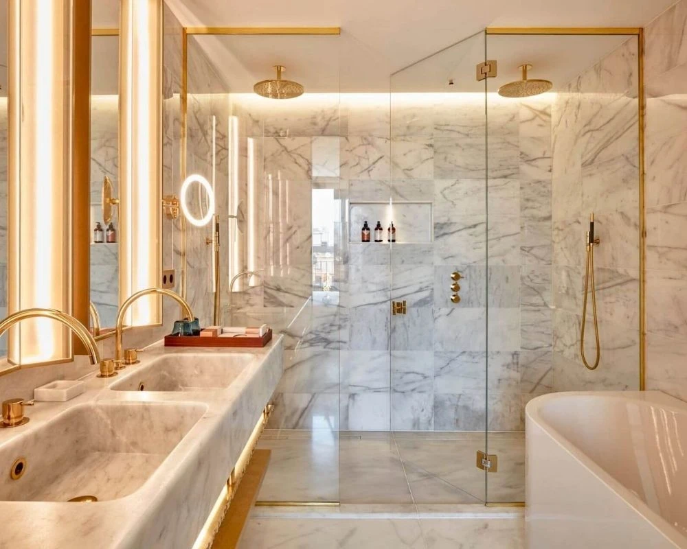 Luxury marble bathroom renovation with gold shower fixtures.