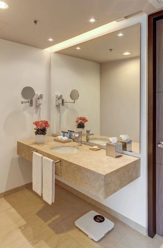 Modern hotel bathroom renovation with stone vanity counter.