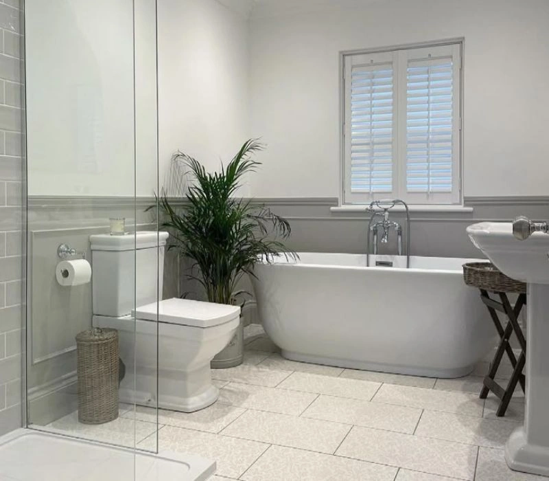 Traditional bathroom renovation with grey wainscoting and bath.