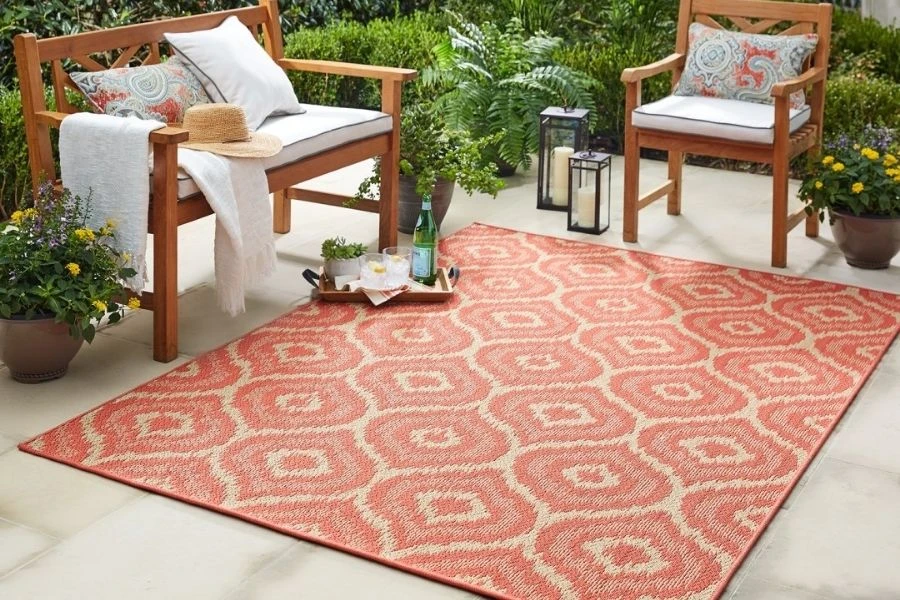 Terracotta outdoor rug with cream geometric patterns on patio.