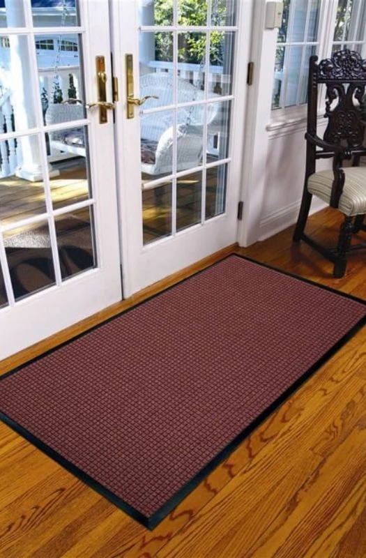 Brown indoor entrance floor mat on wooden floor.