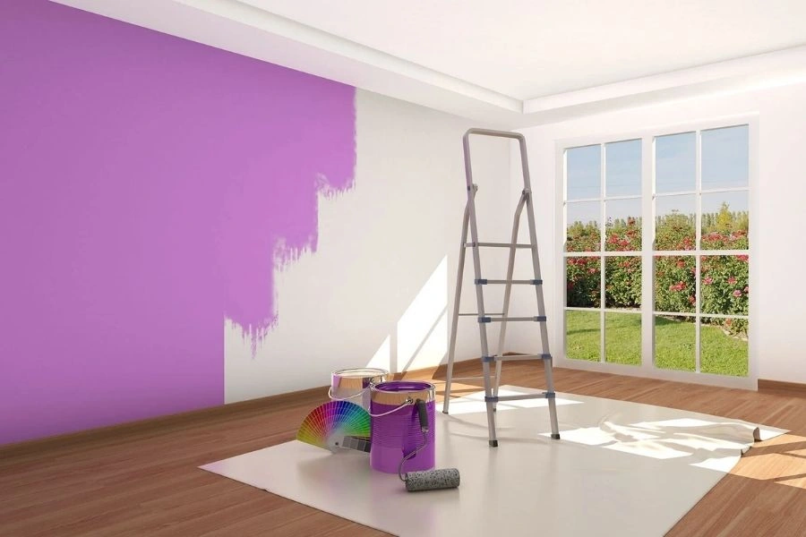 Half-painted purple wall with painting tools in a room.