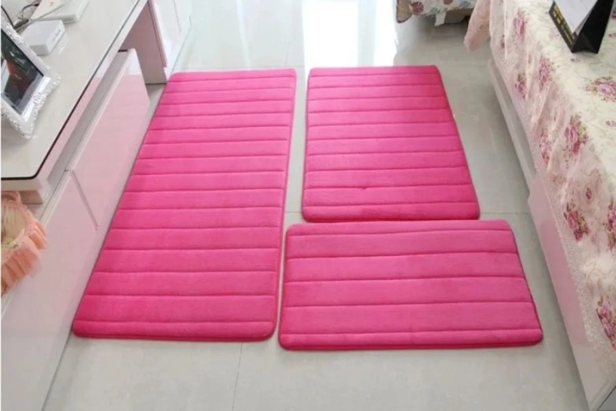 Set of three pink plush memory foam floor mats in a room.